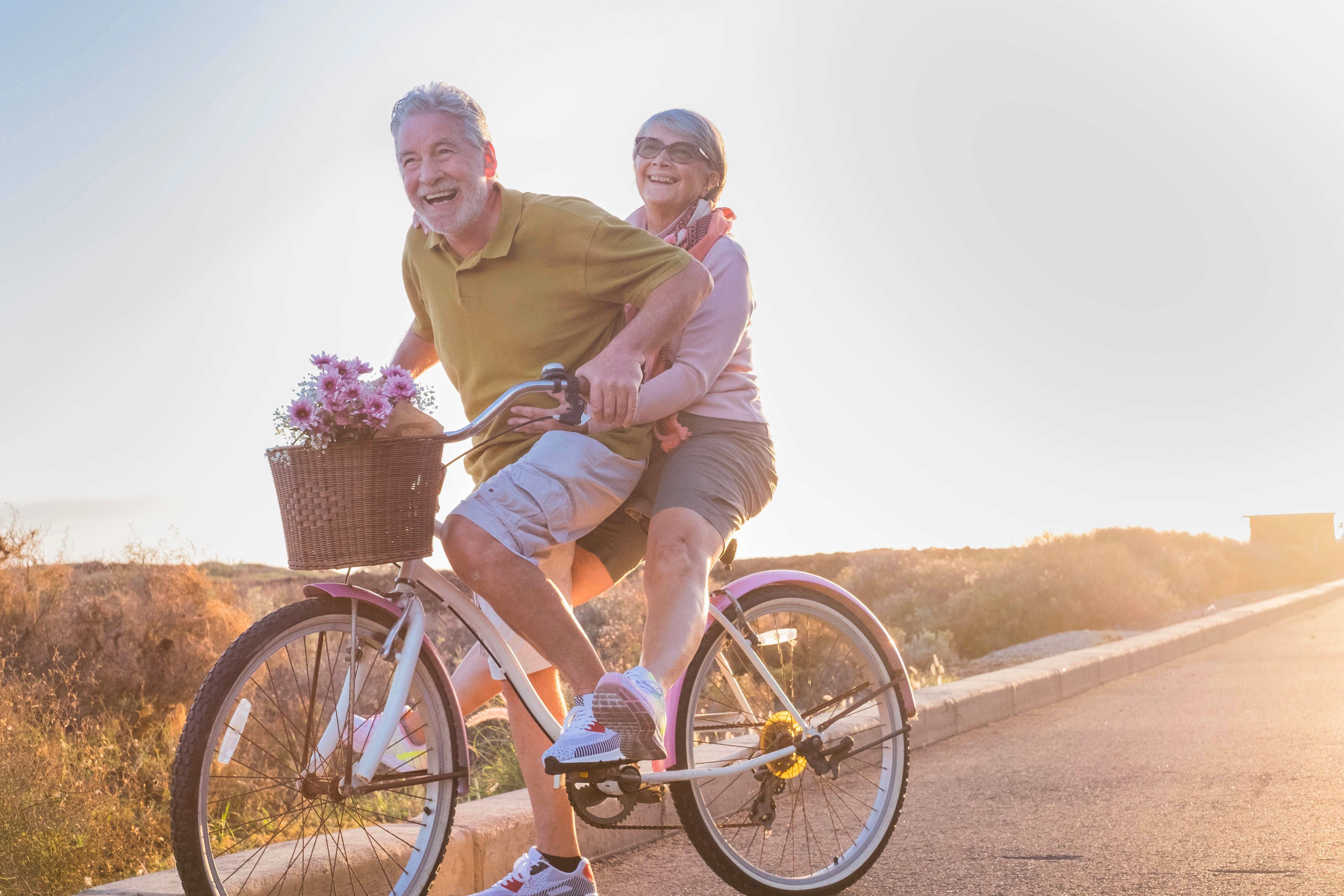 An older couple biking together out in the summer sunshine An older couple biking together out in the summer sunshine